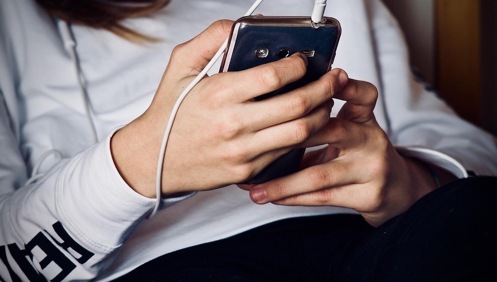 Jugendliche/r mit Handy in der Hand